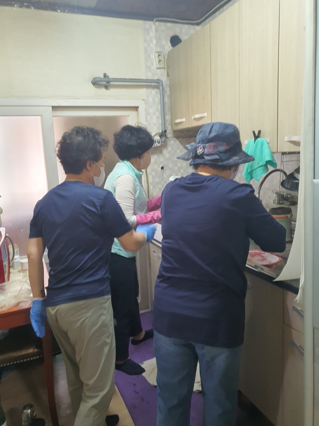 치매예방을 위한 원예치료 및 정리수납 봉사독거노인을 위한 정리수납 봉사에서 봉사자 3명이 싱크데에서 주방 식기를 세척하고있는 모습