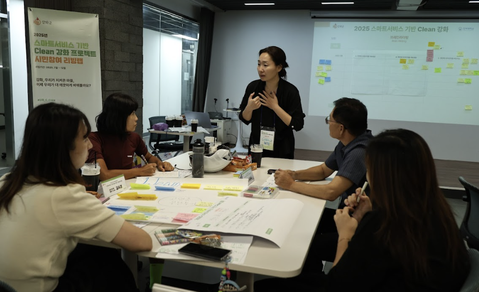 2025년 스마트서비스 기반 clean강화라는 제목의 종이를 들고 있는 두 남녀의 모습