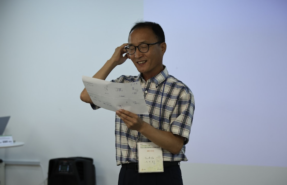 중년의 한 남성이 종이를 들고 웃고 있는 모습