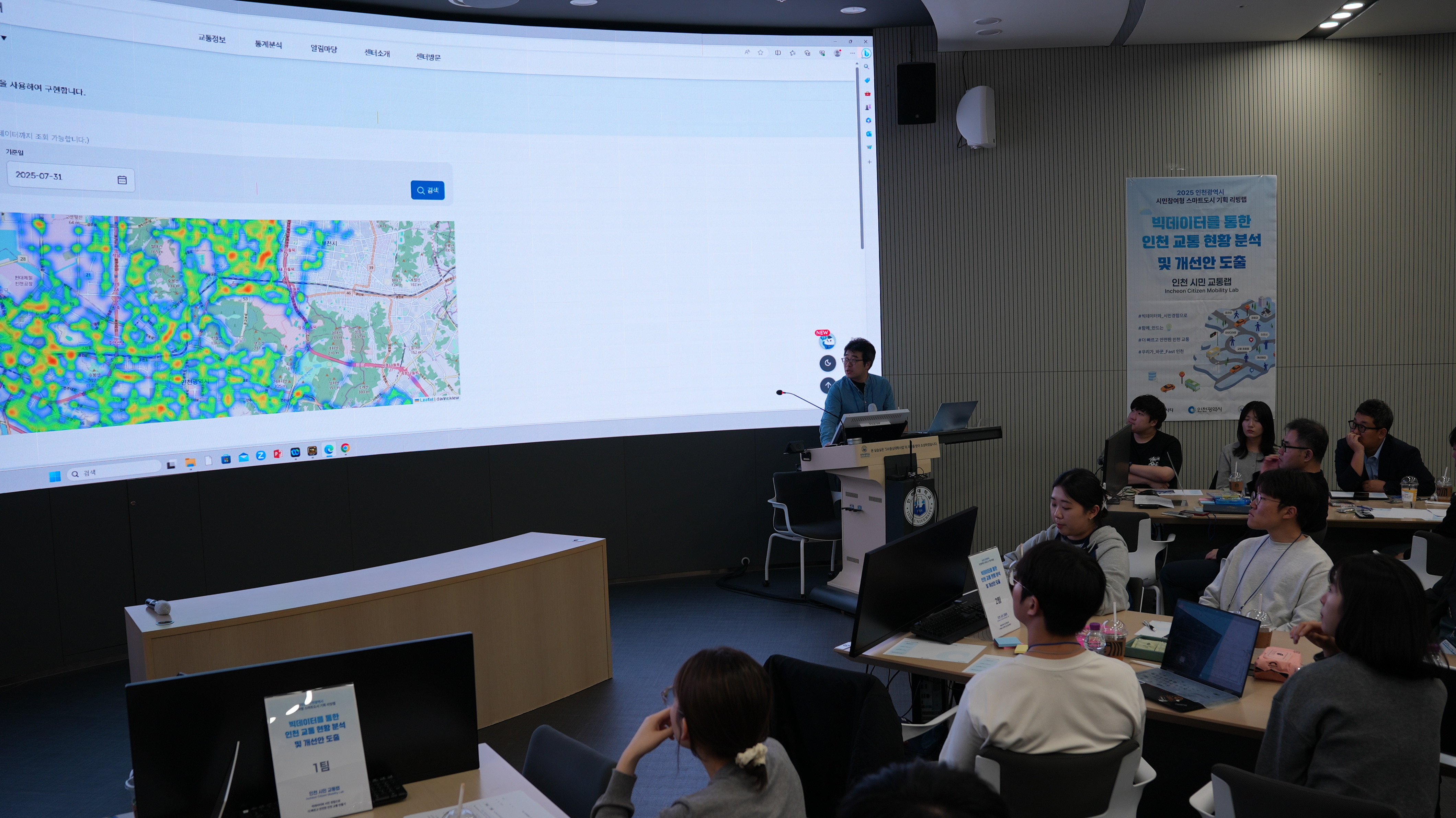 남성 진행자가 지도가 포함된 프레젠테이션을 보여주며 설명하고 있는 모습