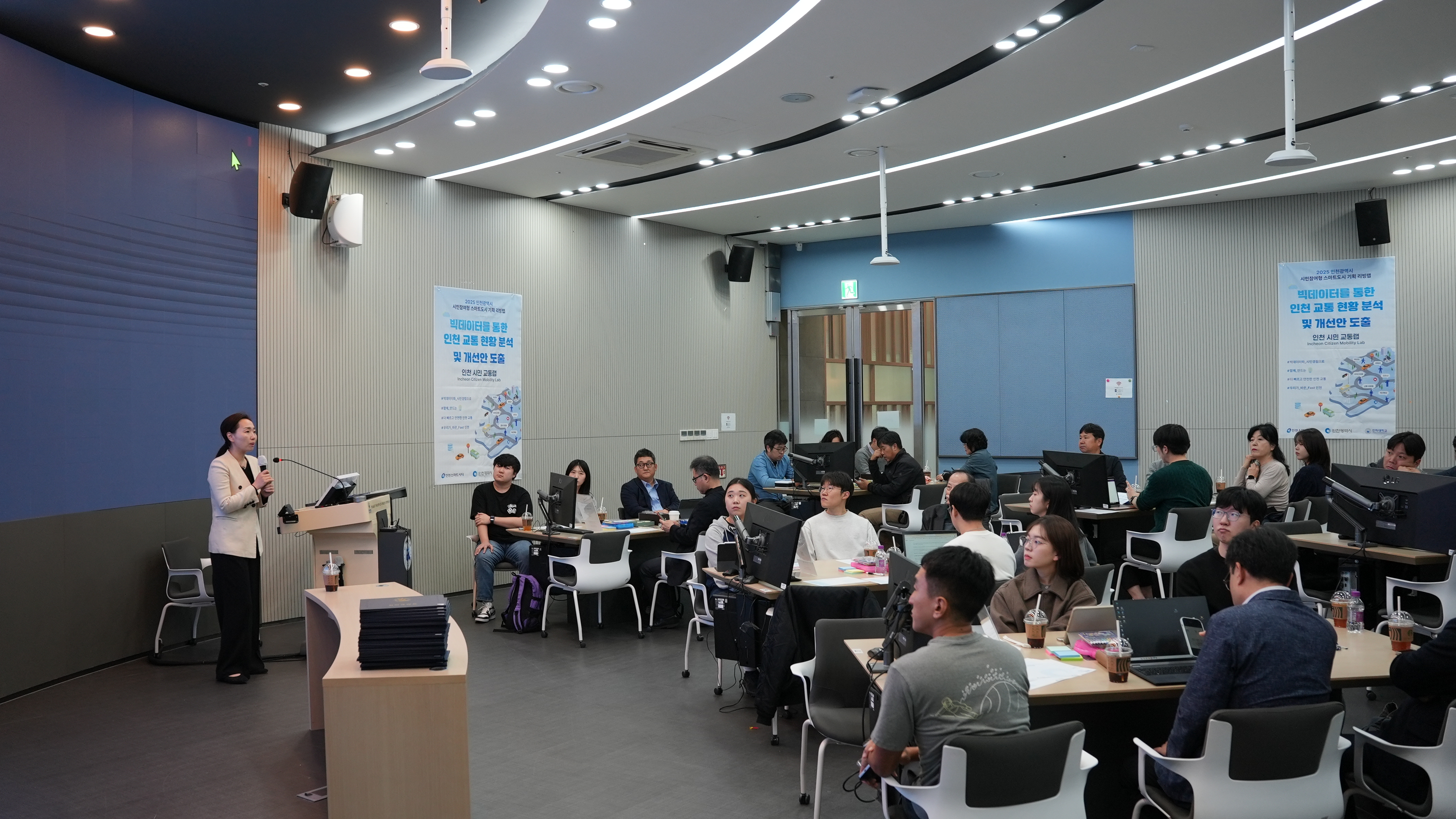 여성 진행자와 좌석에 앉아 경청하고 있는 참석자들의 모습